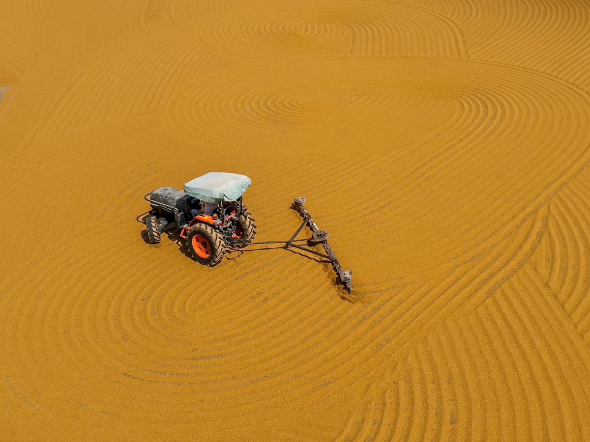 a tractor with plough ploughing brown sand